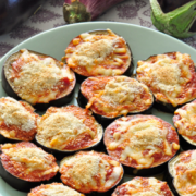 Plato de rodajas de berenjena con salsa roja y mozzarella espolvoreado con migas de pan.