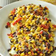 Platter of potatoes stuffed with beans, corn, salsa and sprinkled with melted cheese.