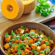 Vibrant harissa roasted butternut squash in a wooden bowl topped with fresh mint and cilantro 