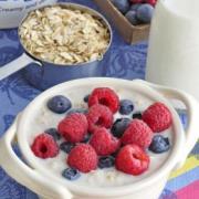 Ceramic bowl with creamy oatmeal topped with raspberries and blueberries.