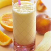 Glass of a creamy orange smoothie with a straw.
