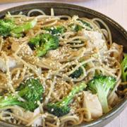 Bowl of noodles, broccoli and chicken with a light sauce and sesame seeds.