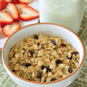 Tazón de avena en hojuelas y pasas servida con leche y fresas.