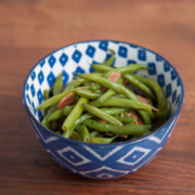 Bowl of green beans with ham and onions.