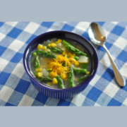 Bowl of soup with asparagus and potatoes topped with cheddar cheese.