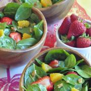 Bowls of spinach salad topped with strawberries and orange slices. 