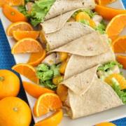 Platter of tortillas filled with lettuce, chicken and oranges. 