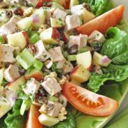 Bowl of turkey cubes, apples and an array of chopped vegetables over a bed of lettuce. 
