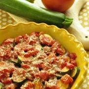 Bowl of baked zucchini with a cheesy tomato sauce. 