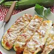 Plate of baked zucchini halves filled with red sauce and melted cheese.