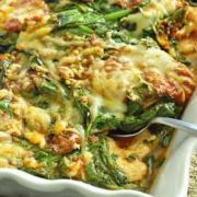 Baking dish with chicken, spinach, sauce and cheese. 