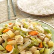 Plate of diced pineapple, vegetables and chicken served with rice.