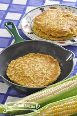 Round, golden corn pancakes displayed on a skillet and plate.