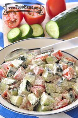 Bowl of chopped cucumber and tomatoes with a creamy dressing.