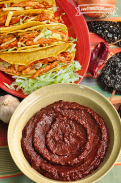 Tazón mediano de salsa espesa de adobo rojo, servida con tacos.