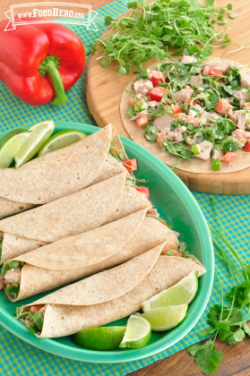 Tortillas folded over a creamy vegetable filled tuna mixture with lime wedges on a plate.
