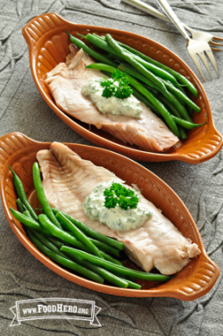 Bowls with fish filets served with green beans and a creamy sauce.