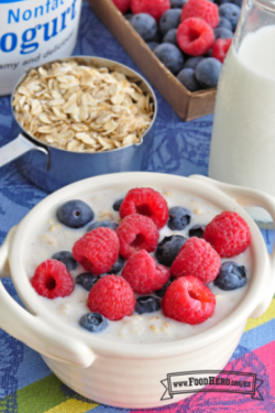 Tazón de cerámica con avena cremosa cubierta con frambuesas y arándanos azules.