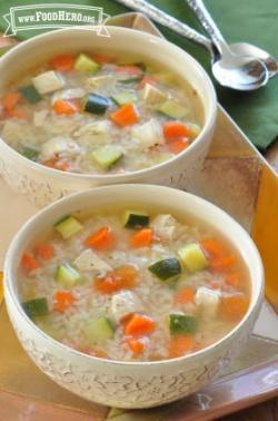 Two bowls of soup filled with rice, chicken and vegetables. 