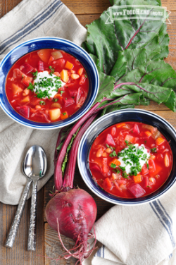 Tazones de vibrante sopa roja de remolacha y verduras con una cucharada de crema agria y perejil.