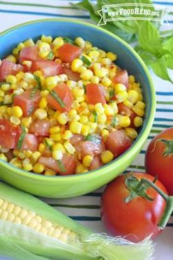 Corn and tomato mix with dressing in a small bowl.