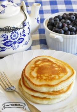 Stack of golden pancakes with a side of blueberries.