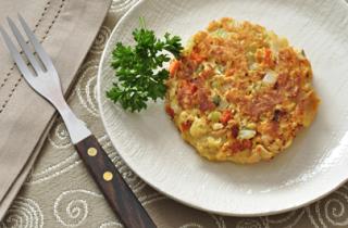 a salmon patty on a white dish with a sprig of parsley as garnish