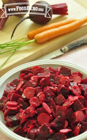 Sliced carrots and beets are mixed with a light dressing and displayed in a salad bowl.
