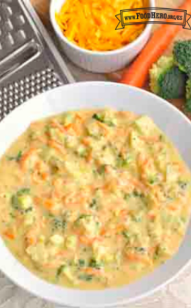 Un tazón de sopa caliente hecha con queso cheddar, zanahorias y brócoli.