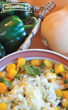 Bowl of seasoned butternut squash topped with shredded cheese.