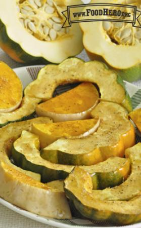 Baked crescent shaped acorn squash slices sprinkled with seasoning.