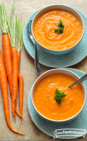 Tazones de sopa de zanahoria suave en platos para servir.