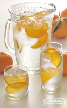 Pitcher of ice water with orange wedges. 