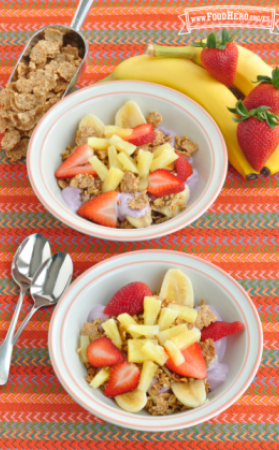 Tazones pequeños de yogur cubiertos con cereal y una colorida combinación de frutas.