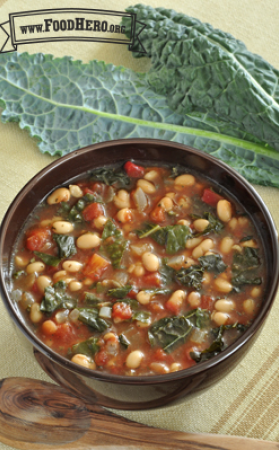Bowl of soup with a tomato base, kale and beans 
