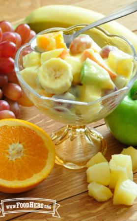 Footed glass dish with a creamy fruit salad. 