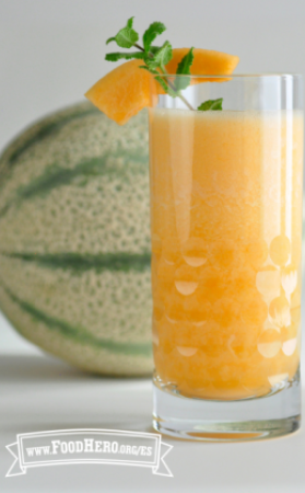Vaso lleno de una bebida de jugo de naranja brillante adornada con menta. 