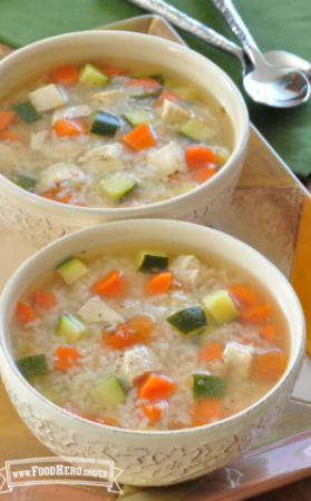 Dos tazones de sopa rellenos de arroz, pollo y verduras.