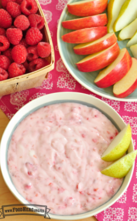 Tazón de dip de frambuesas con yogur servido con rodajas de manzana y pera.