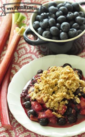 Bowl of baked rhubarb and blueberries with a crumbly oat topping. 