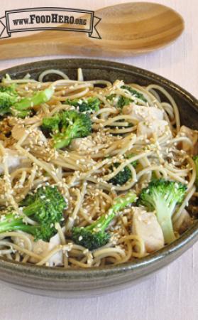 Bowl of noodles, broccoli and chicken with a light sauce and sesame seeds.