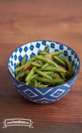 Bowl of green beans with ham and onions.