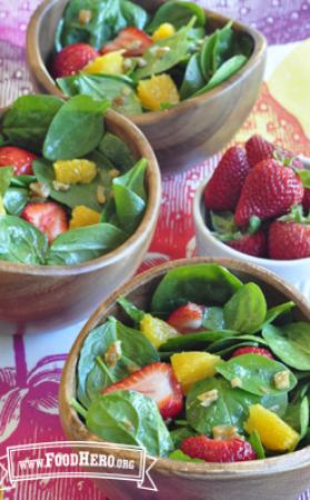 Bowls of spinach salad topped with strawberries and orange slices. 