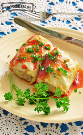 Two tightly wrapped cabbage rolls covered in tomato sauce with a parsley garnish.