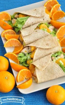 Platter of tortillas filled with lettuce, chicken and oranges. 