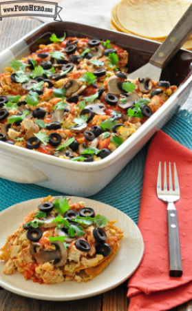Casserole dish with a tofu and vegetable mix topped with black olives and cilantro.