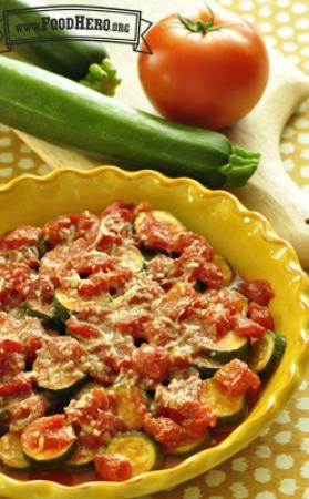 Bowl of baked zucchini with a cheesy tomato sauce. 