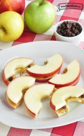 Crispy apple slices with peanut butter and raisin filling are shown on a plate.