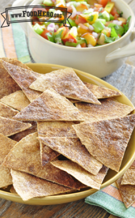 Tortilla chips sprinkled with cinnamon are displayed on a platter with a bowl of peach salsa for dipping.