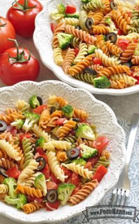 Bowls of colorful spiral pasta with olives and broccoli. 